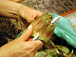 Sempre aiutandoti con il coltello, taglia parte delle foglie esterne e soprattutto la parte superiore dei carciofi.