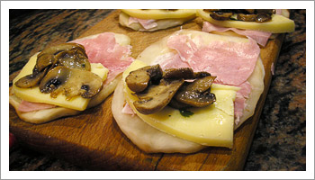 Aggiungi una fettina di prosciutto cotto, una fettina di formaggio e i funghi.