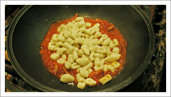 Scola gli gnocchi un minuto dopo che sono riaffiorati in superficie e trasferiscili nella padella del sugo.
