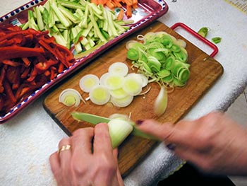 Per prima cosa prepara le verdure: taglia il porro a rondelle, le carote, le zucchine e i peperoni a julienne