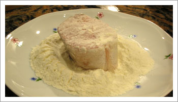 Versa della farina in un piattino e passaci i tranci di merluzzo, ricoprendone ogni parte.