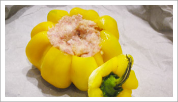 Riempi i peperoni con il composto appena preparato. Copri i peperoni con la calotta e disponili in una pirofila con la base foderata da carta da forno.