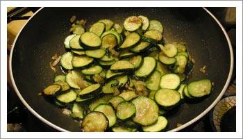 Nel frattempo pulisci e lava le zucchine, riduci a rondelle e cuoci in un tegame con poco olio e della cipolla tagliata. Il tutto deve appassire.