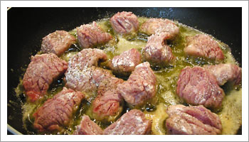 Taglia la carne a tocchetti; infarinali e lasciali rosolare in una casseruola con 3 cucchiai di olio e una noce di burro.