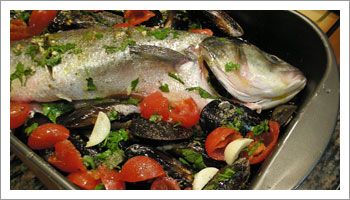 Adagia il pesce in una teglia da forno, aggiungi le cozze, il pomodoro, l'aglio a pezzettoni, del prezzemolo tritato a mano, l'olio e del vino bianco. Aggiungi poco sale e del pepe.