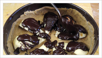 Sistema i quarti di pera all'interno della tortiera e colaci sopra la cioccolata fondente