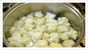 把耶菜花切成小块，洗净并放入一个装有冷的淡盐水的锅中浸泡