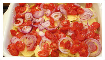Termina con uno strato di patate, pomodori, cipolle a rondelle e parmigiano grattugiato. Condisci con olio, sale e pepe